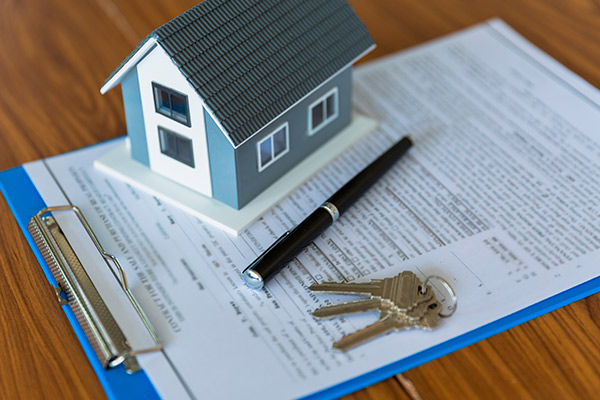 A house model alongside keys, a pen, and paper, representing resources for first-time home buyers in South Texas.