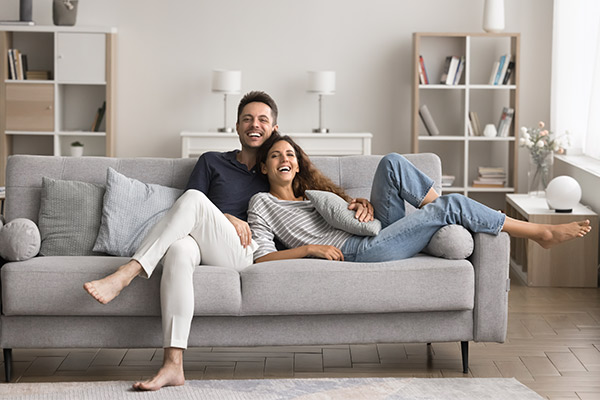 A man and woman relax on a couch in a cozy living room, discussing first-time home buyer programs in South Texas.