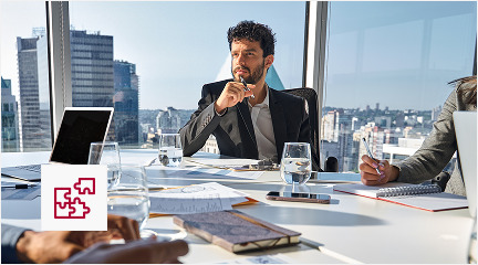 Business team seated at a table, engaged in discussion with a laptop open among them.