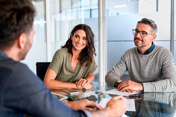 Smiling mature couple meeting with bank manager for investment. Mid adult woman with husband listening to businessman during meeting in conference room. Middle aged couple meeting loan advisor.
