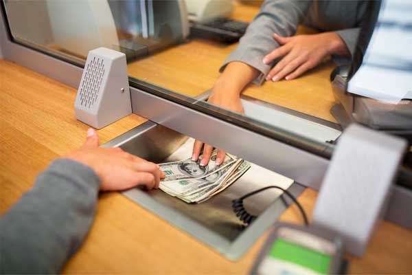 people, withdrawal, saving and finance concept - clerk giving cash money to customer at bank office or currency exchanger